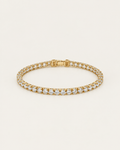 Gold-tone tennis bracelet with a continuous row of clear stone accents, laid out with the clasp visible.