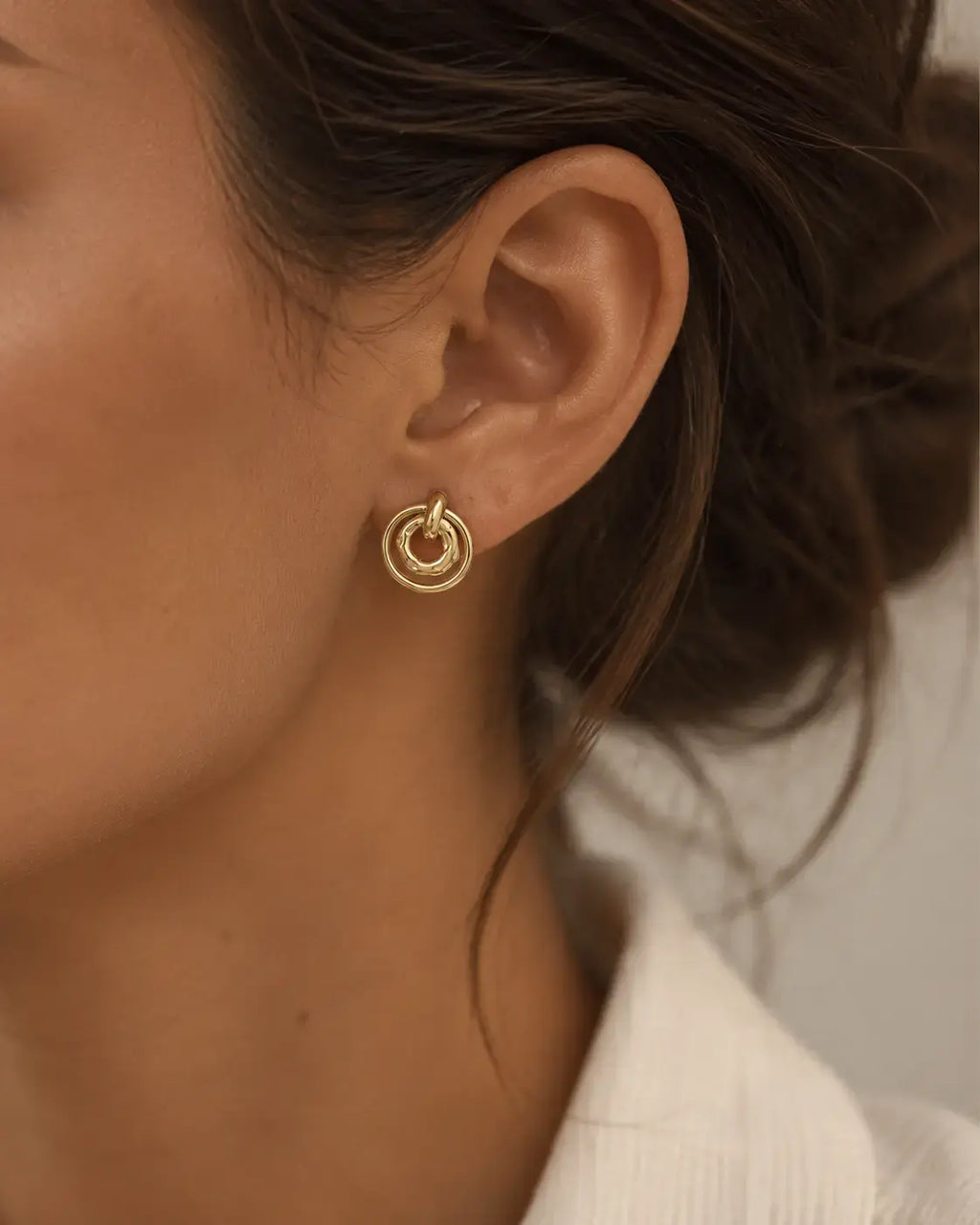 Close-up of a concentric circle drop earring on the ear.