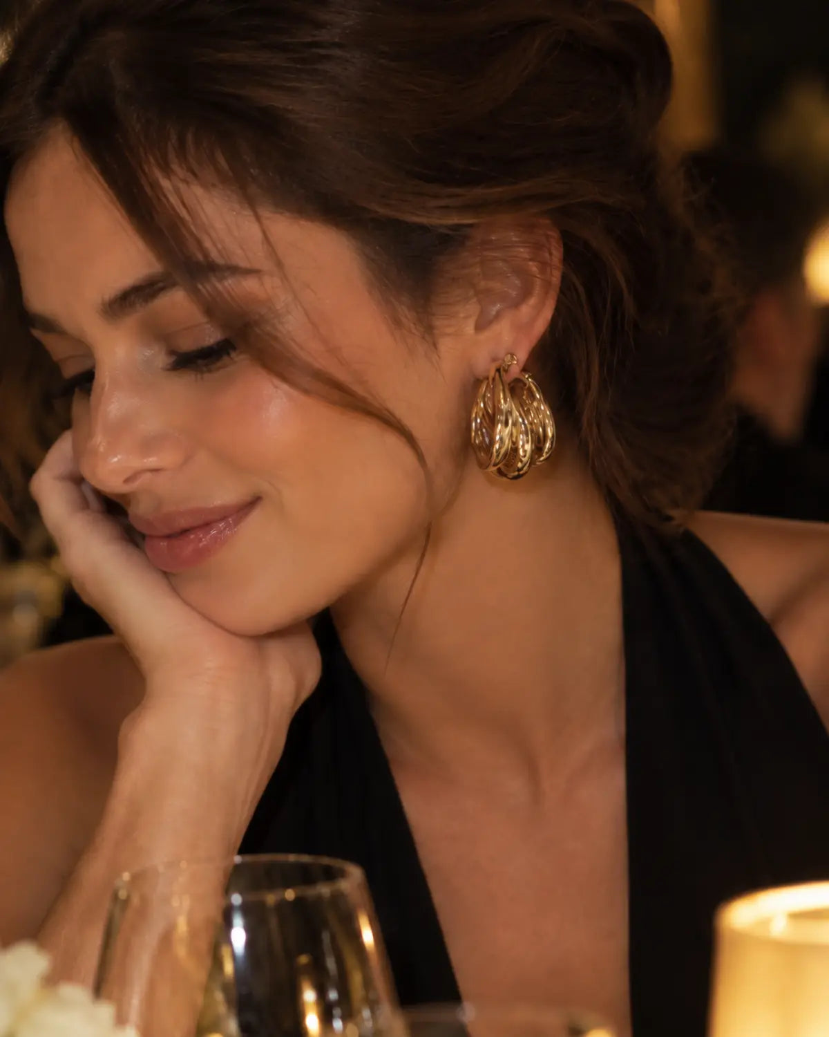 Three-strand gold-tone hoop earring worn in a downward-looking portrait.