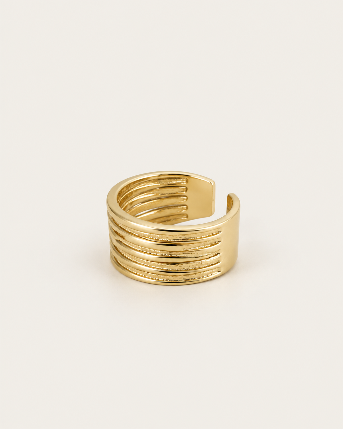 Gold-tone open band ring with multiple parallel rails, angled view showing the open back.