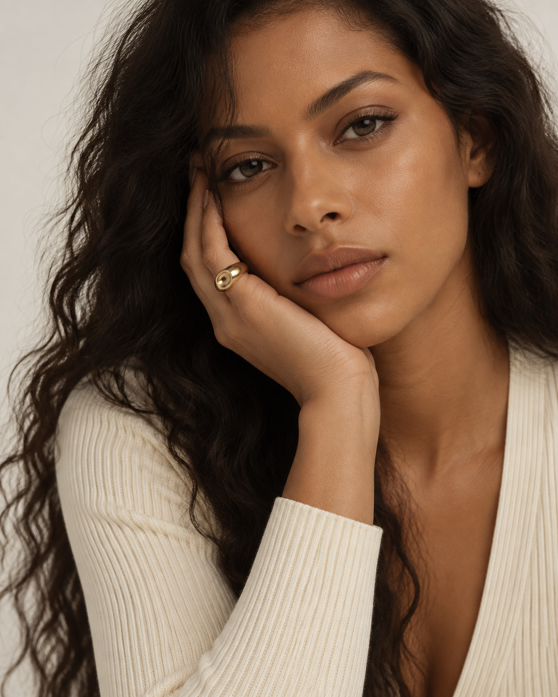 Gold-tone dome ring with a concave circular centre, worn with the hand supporting the cheek.