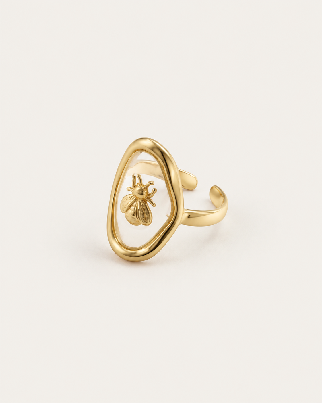 Gold-tone ring with a bee inside an open oval frame, angled view showing the open band.