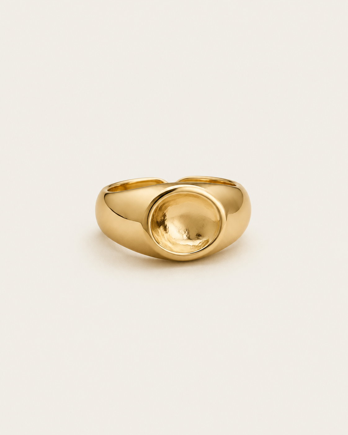 Gold-tone dome ring with a concave circular centre, front view.