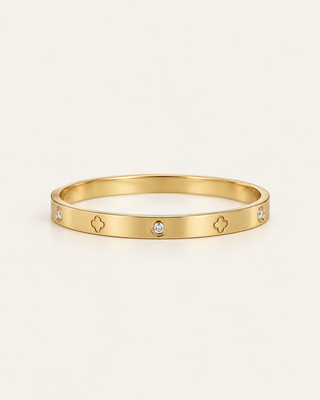Gold-tone bangle with clover outlines and stone accents, front view.