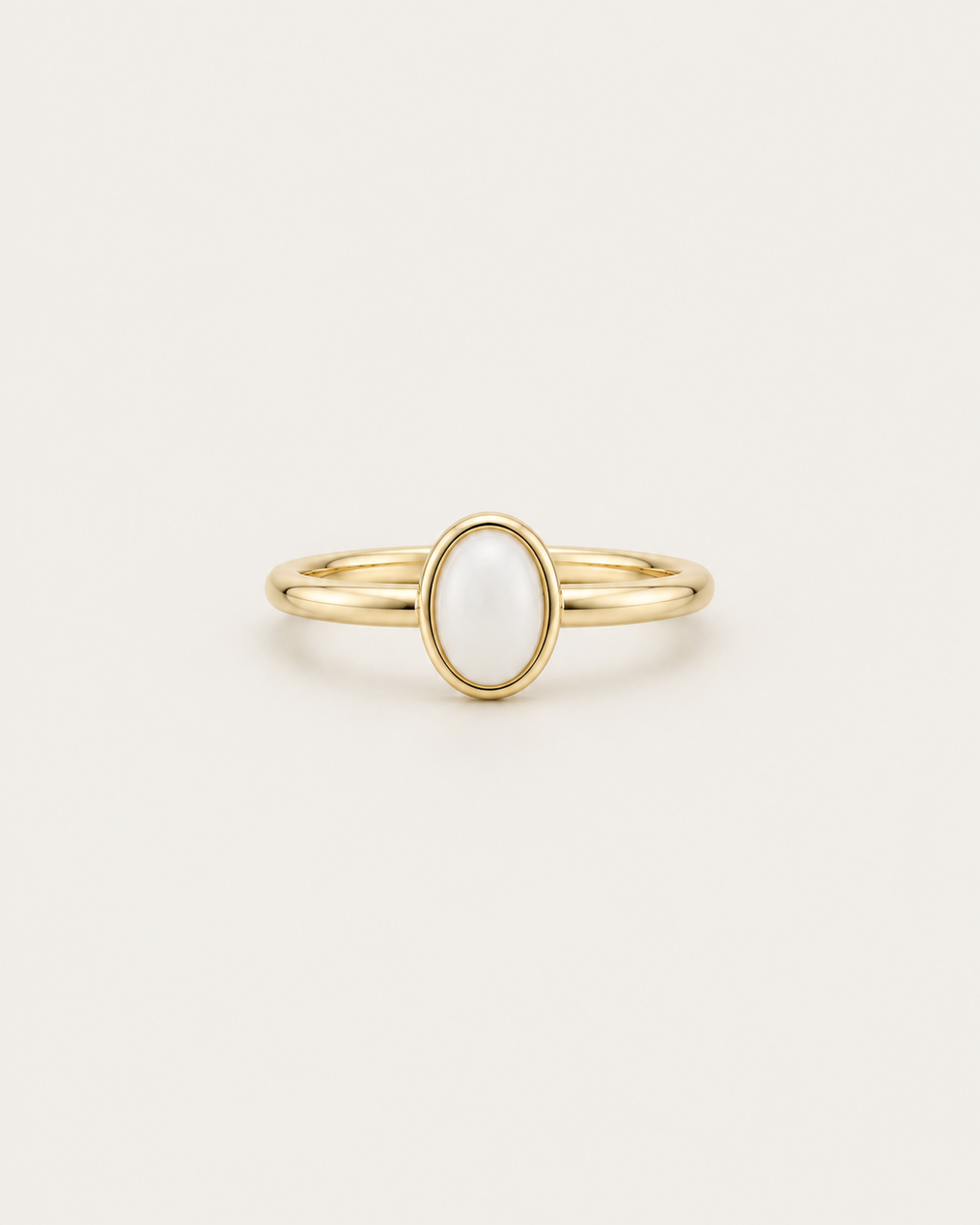 Slim gold-tone ring with a white oval bezel accent, front view.