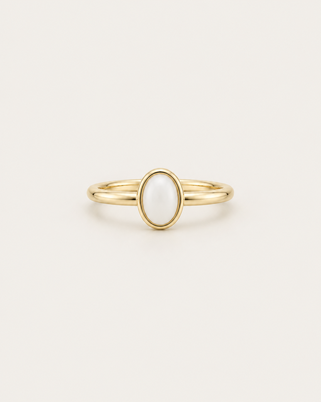 Slim gold-tone ring with a white oval bezel accent, front view.