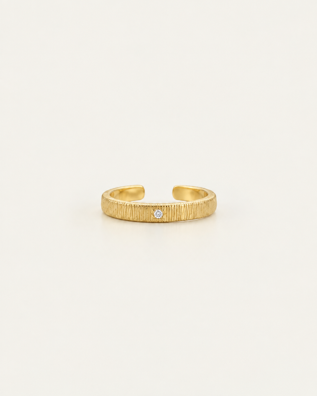 Gold-tone textured ring with a small stone accent, front view of the open band.