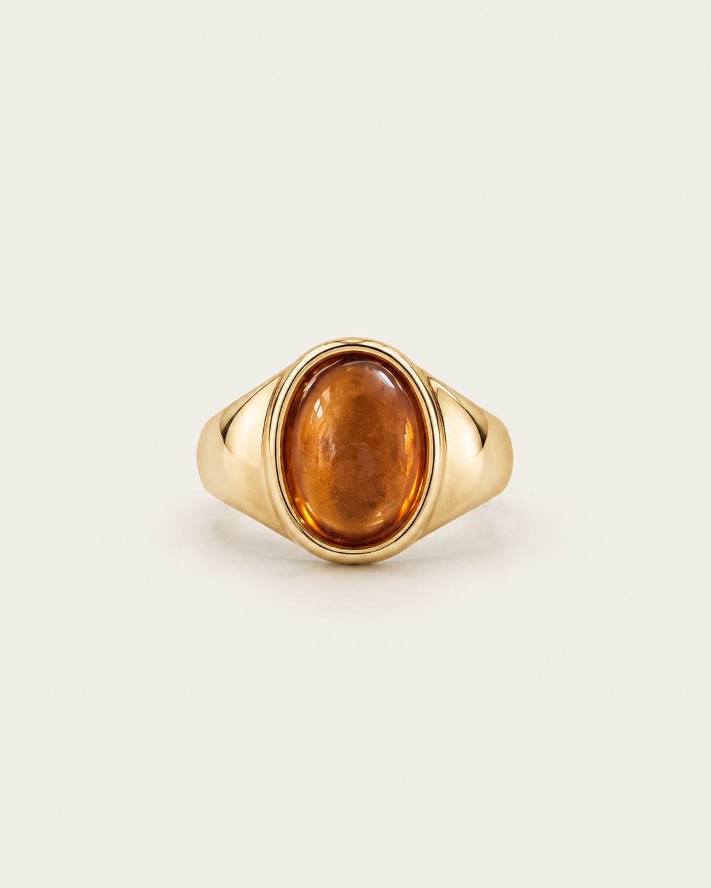 Gold-tone signet ring with a raised warm-brown oval accent, front view.