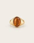 Gold-tone signet ring with a raised warm-brown oval accent, front view.