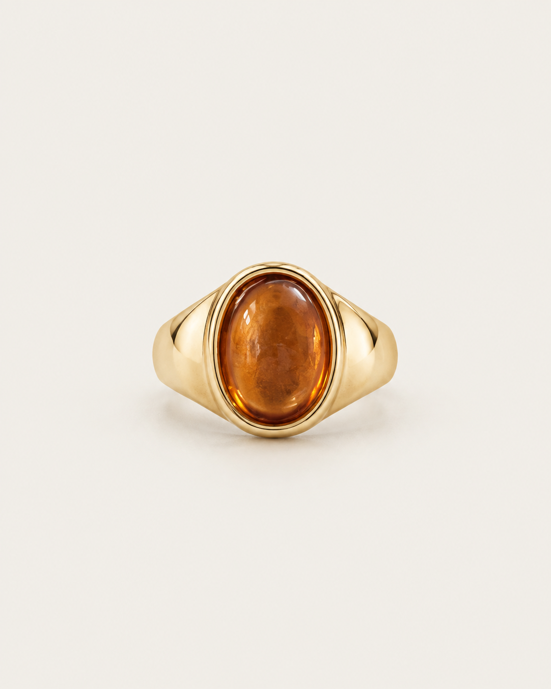 Gold-tone signet ring with a raised warm-brown oval accent, front view.