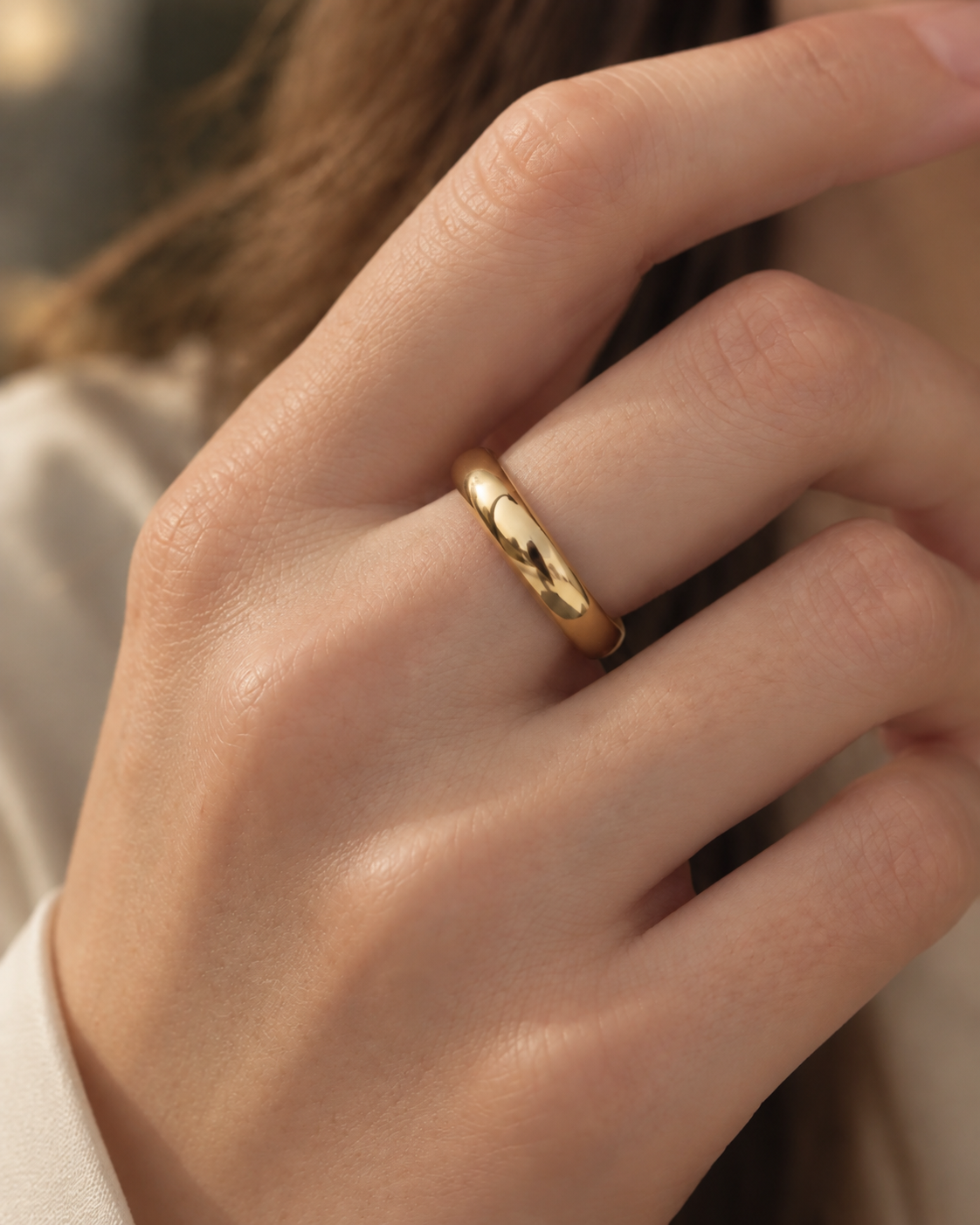 Gold-tone smooth dome band ring, close-up of the rounded band on a finger.