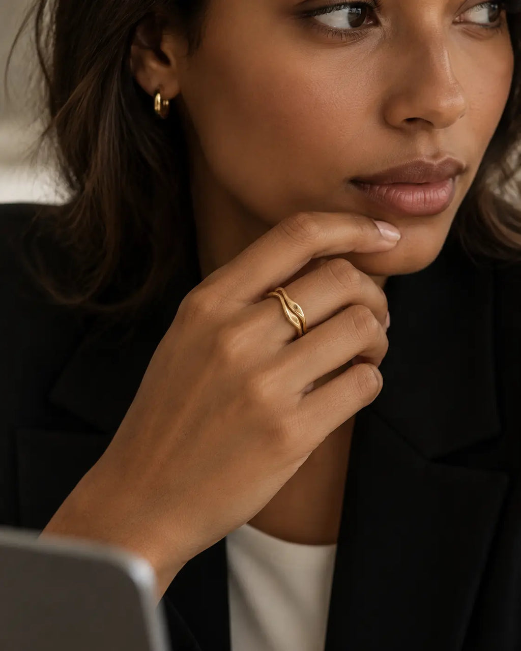 Set of two gold-tone wave stacking rings, worn together on a hand near the chin.