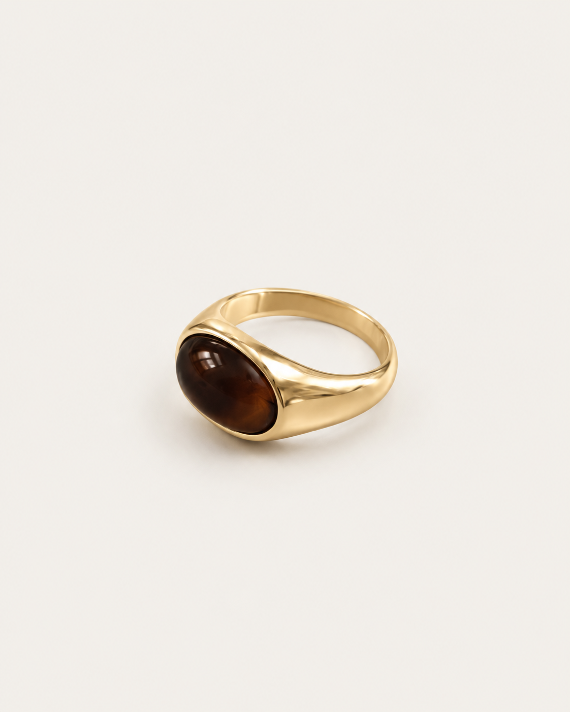 Gold-tone ring with a horizontal brown oval accent, angled view showing the setting and band.