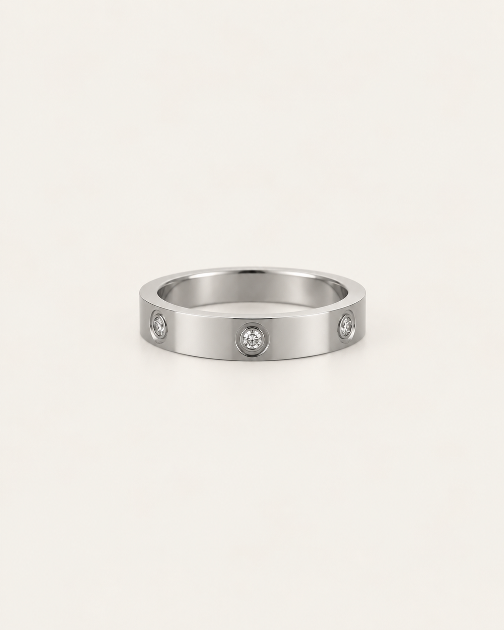 Silver-tone band ring with spaced round bezel-set stone accents, shown on its own.