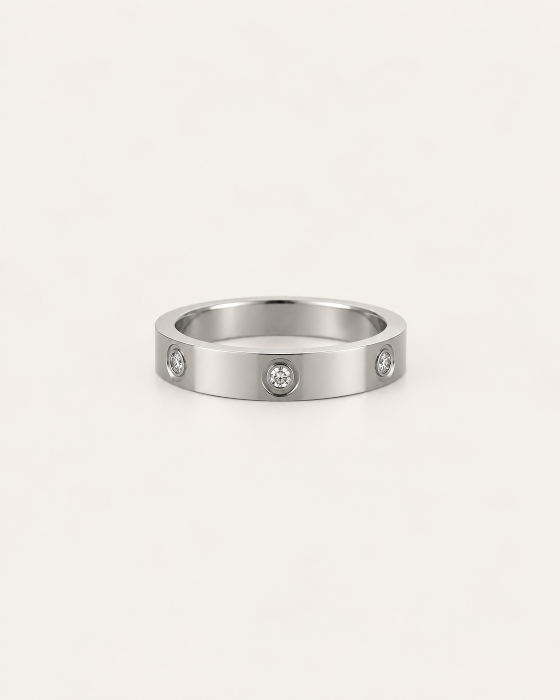 Silver-tone band ring with spaced round bezel-set stone accents, shown on its own.