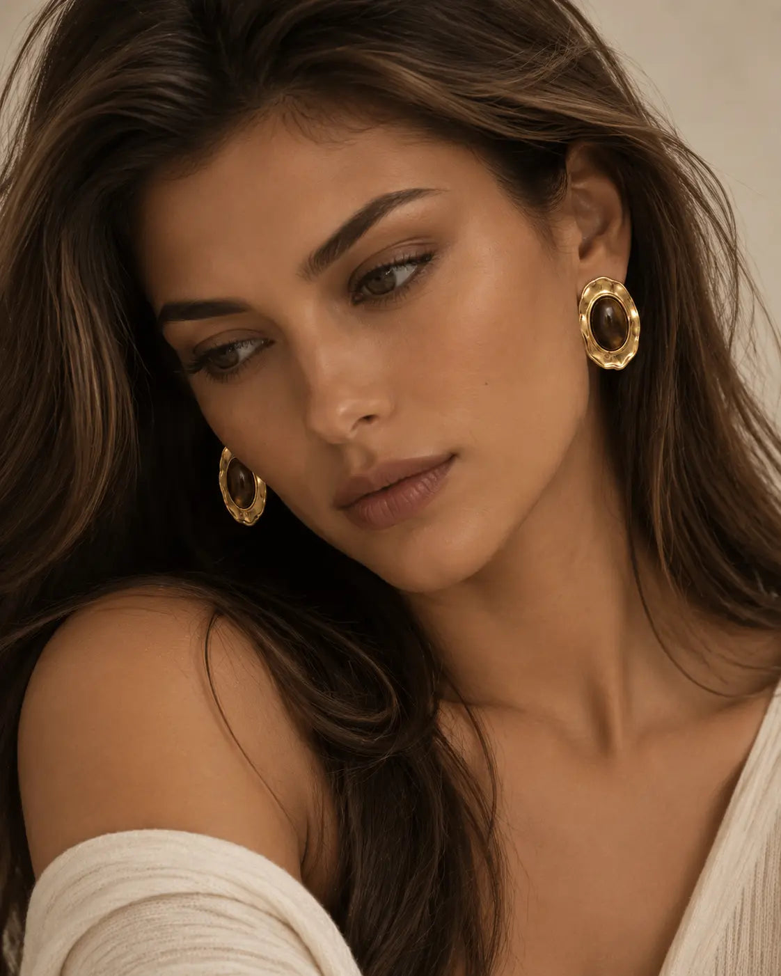 Brown oval stud earrings worn in a portrait.