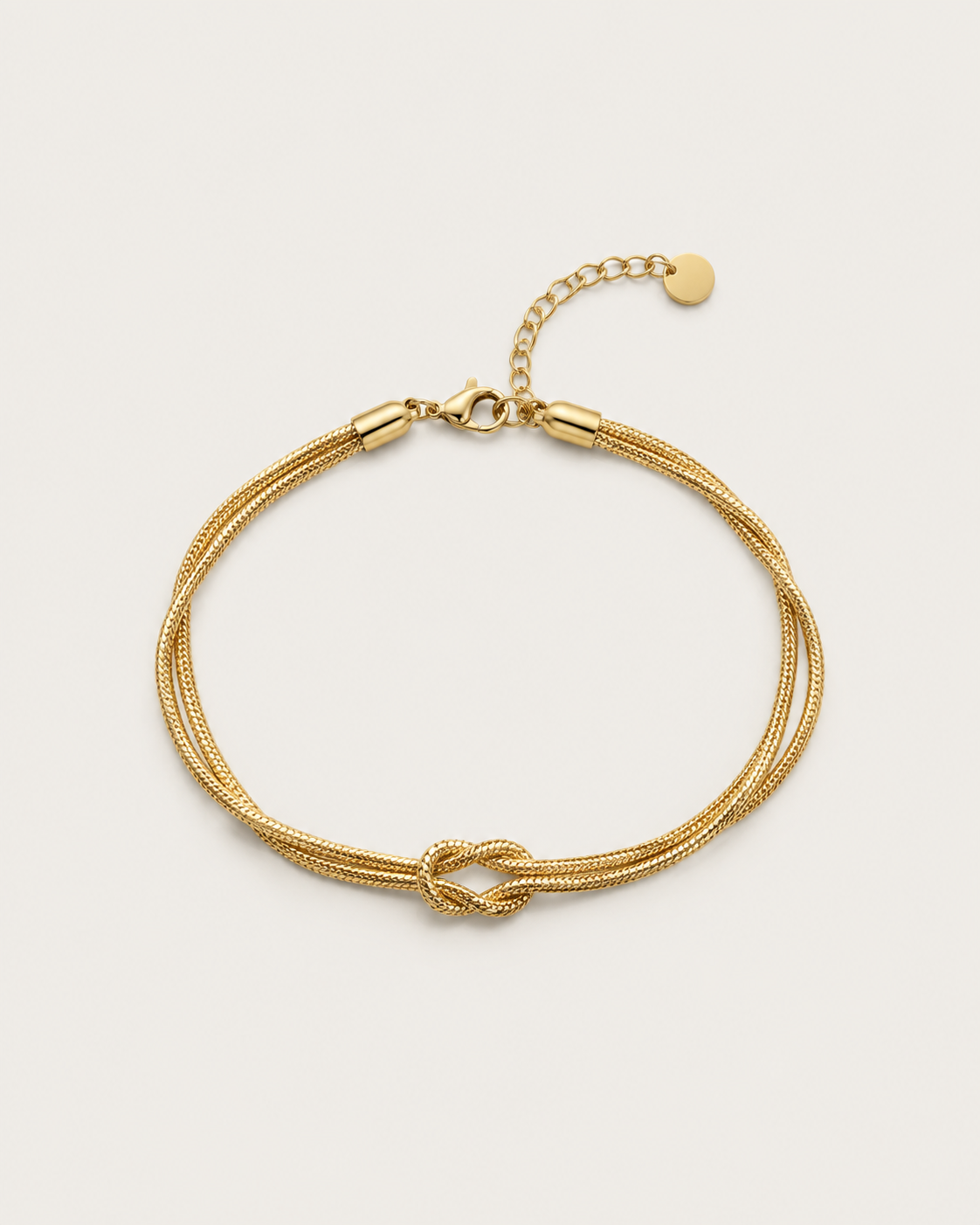 Gold-tone double-chain bracelet with a central knot, laid out with its extension chain.