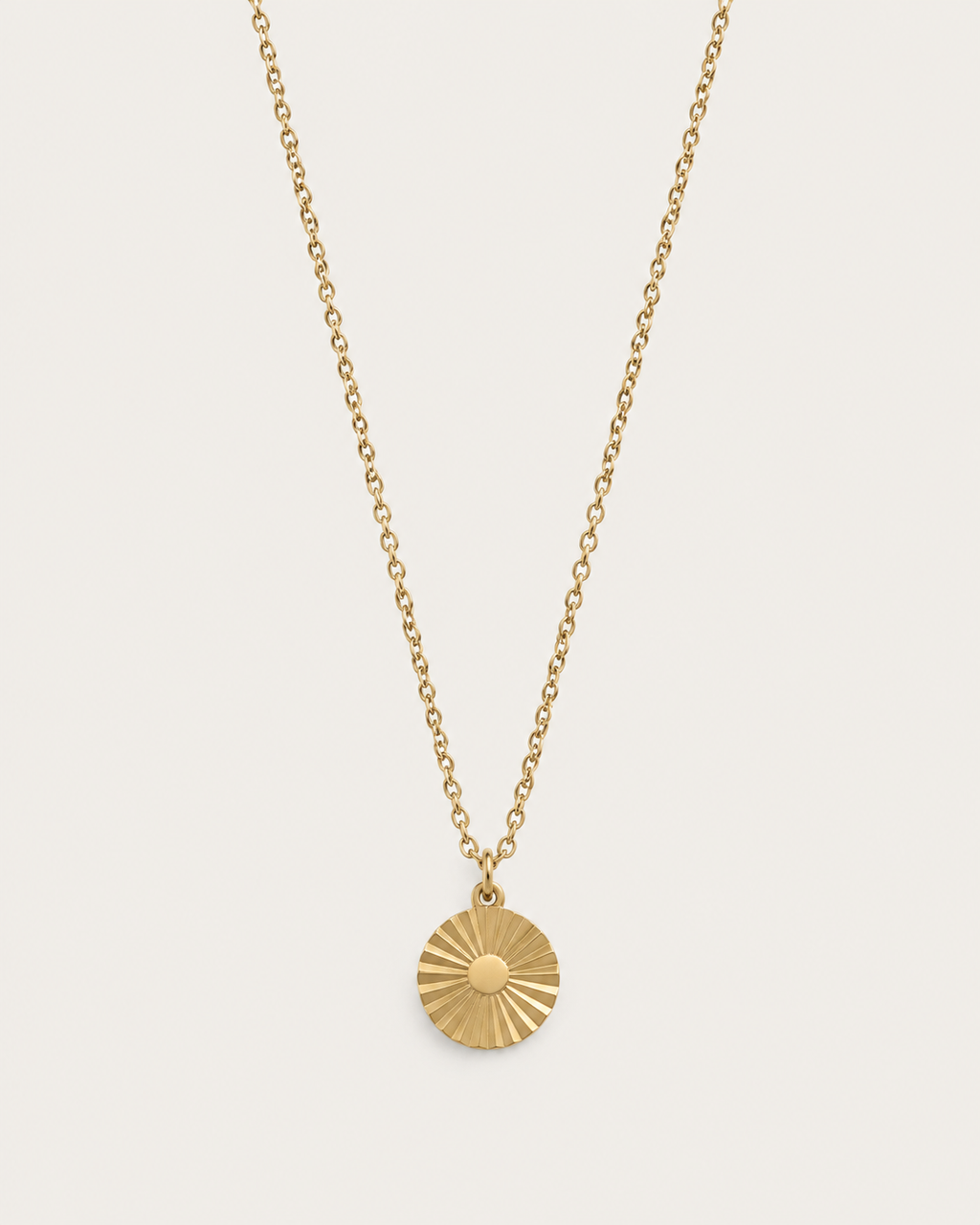 Gold-tone necklace with a round sunburst coin pendant, front view.