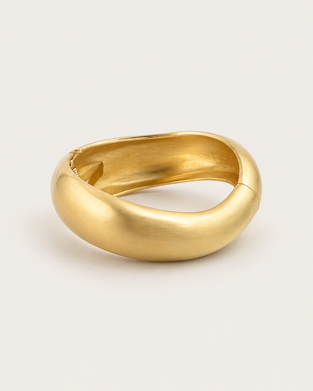 Gold-tone rounded contour bangle with a brushed-looking surface, rotated view showing the irregular inner outline.