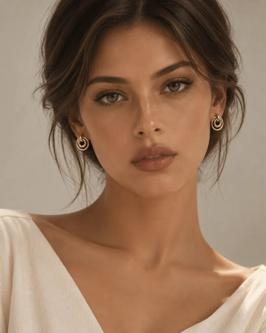 Gold-tone concentric circle earrings worn in a front-facing portrait.