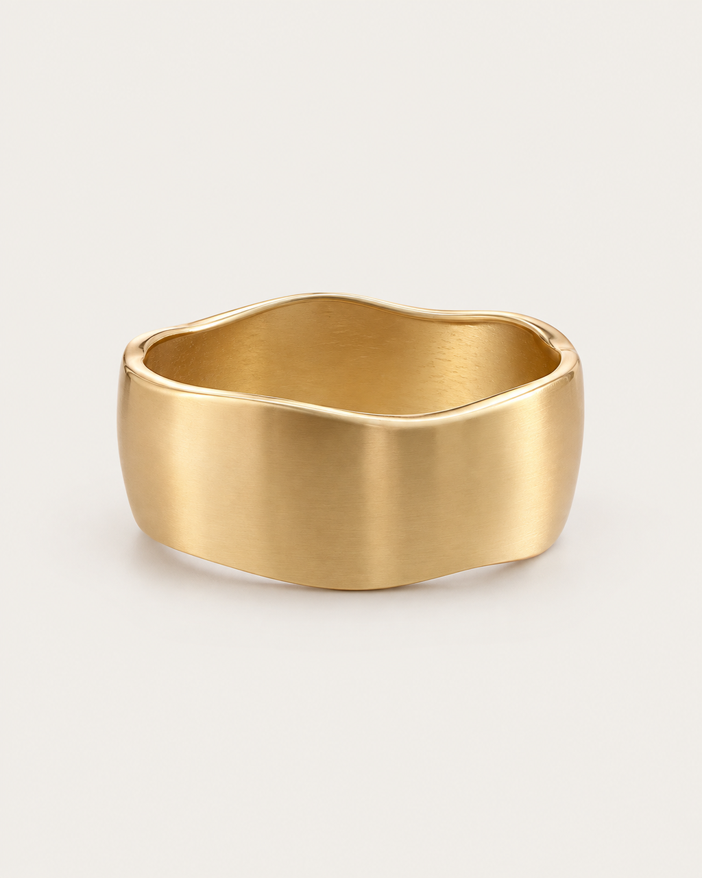 Gold-tone wide bangle with a satin-looking surface and wavy edges, front view.