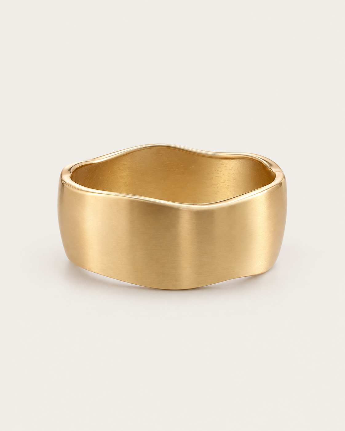 Gold-tone wide bangle with a satin-looking surface and wavy edges, front view.