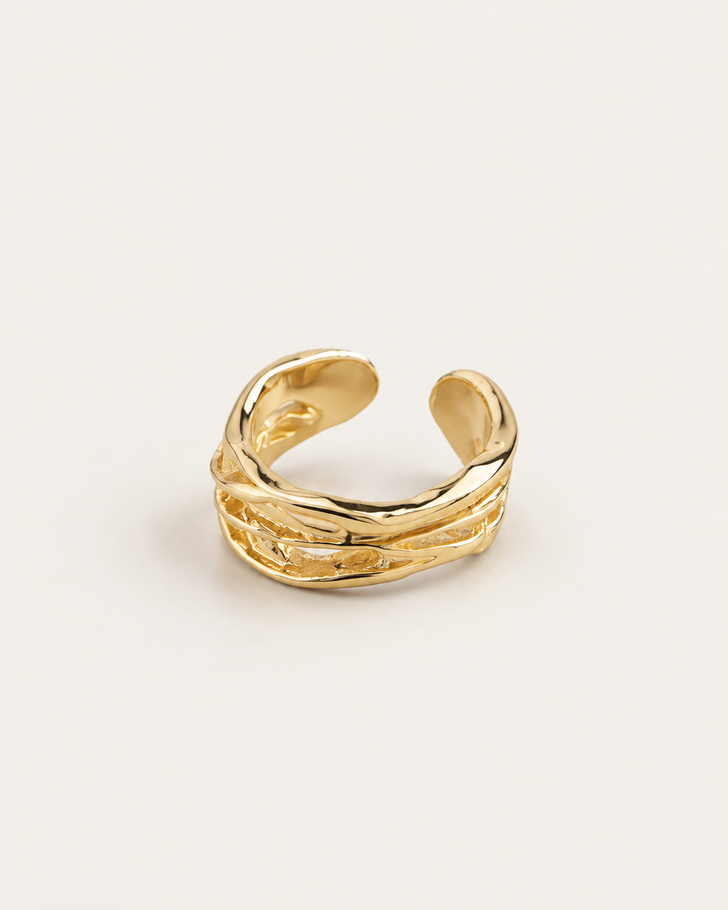 Gold-tone open ring with raised rails and irregular cutouts, rear angle showing the open band.