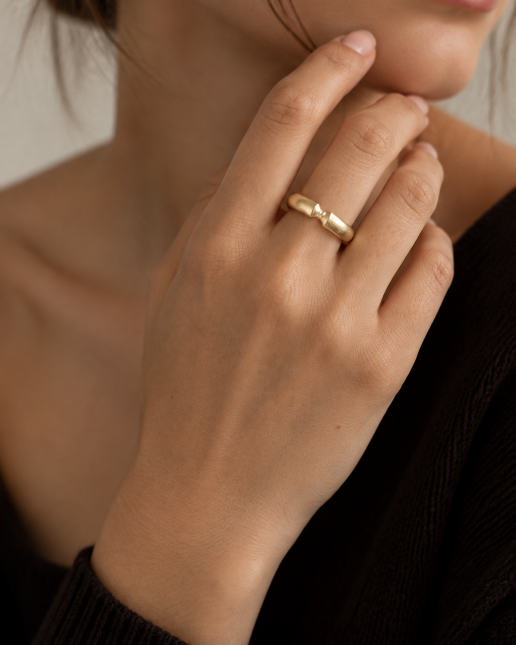 Gold-tone ribbon-knot ring, close-up of the knot on a finger.