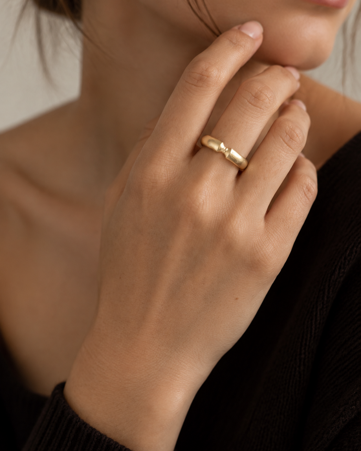 Gold-tone ribbon-knot ring, close-up of the knot on a finger.