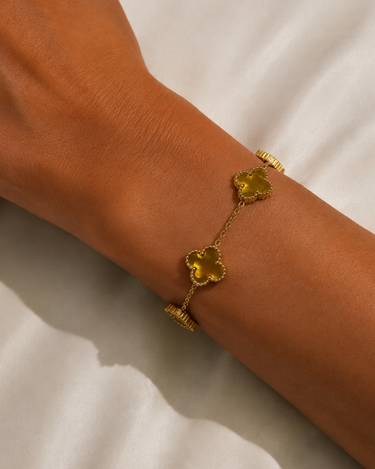 Gold-tone chain bracelet with five clover stations, worn with gold-tone clover stations across the wrist.