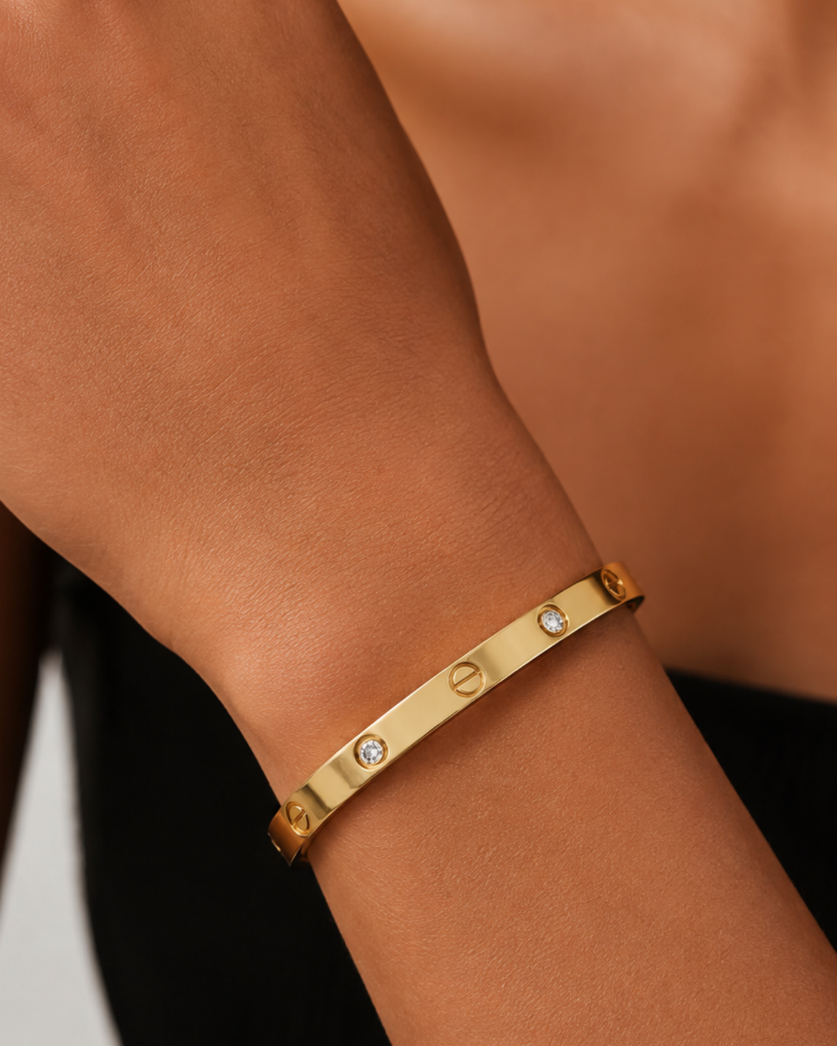 Gold-tone bangle with screw motifs and alternating stone accents, close-up of the screw motifs and stone accents on the wrist.