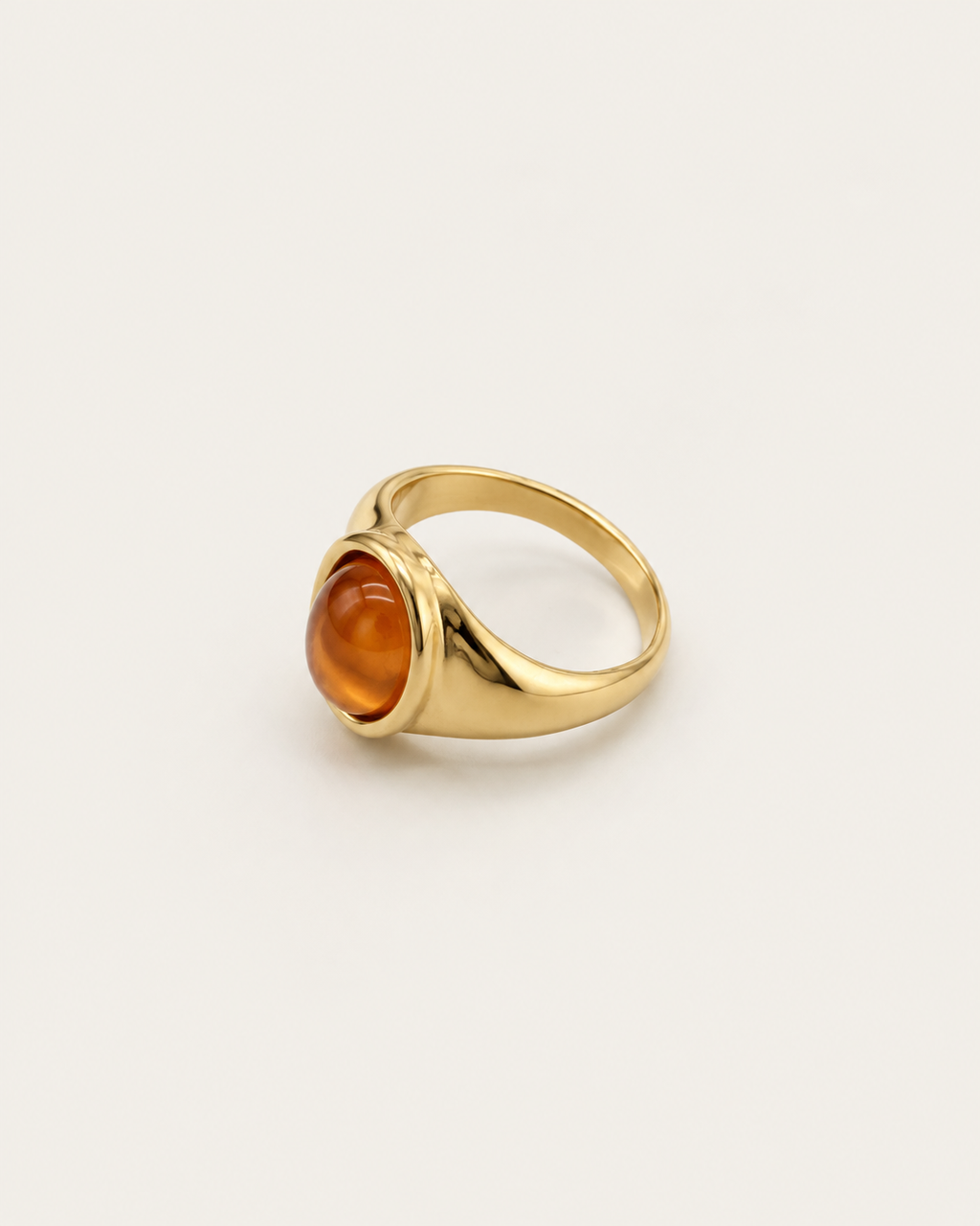 Gold-tone signet ring with a raised warm-brown oval accent, side view showing the shoulders.