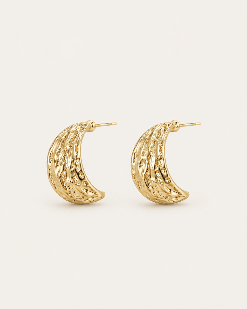 Pair of broad gold-tone hoop earrings with an irregular textured surface, angled view showing the hoop openings.