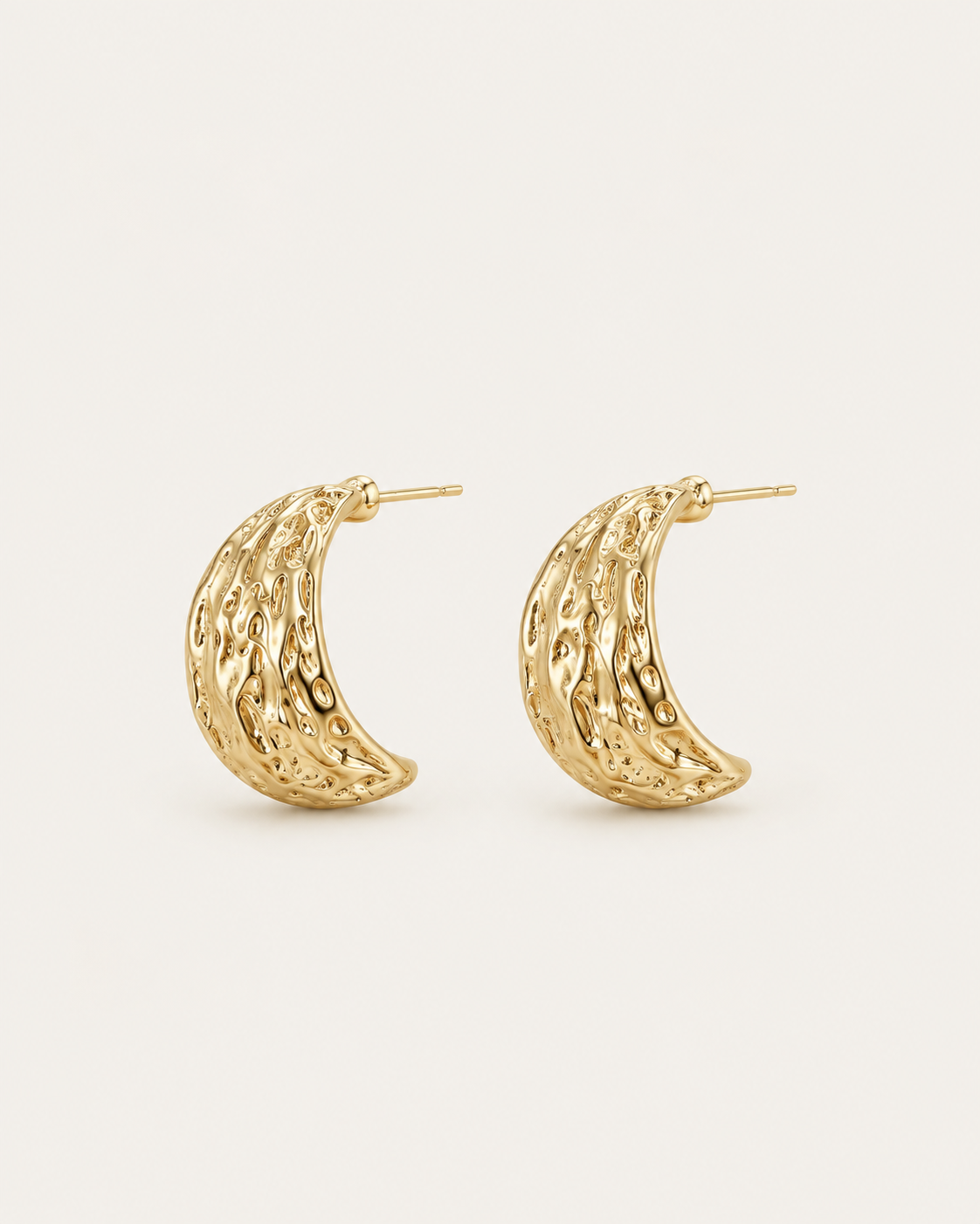 Pair of broad gold-tone hoop earrings with an irregular textured surface, angled view showing the hoop openings.