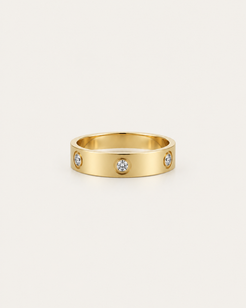 Gold-tone band ring with spaced round bezel-set stone accents, front view.
