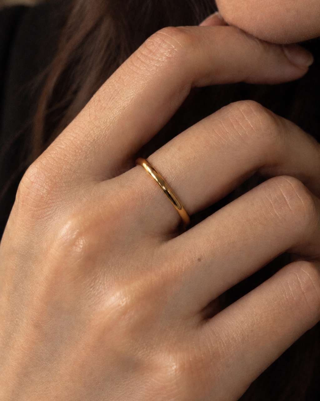 Slim plain gold-tone band ring, close-up of the narrow band on a finger.