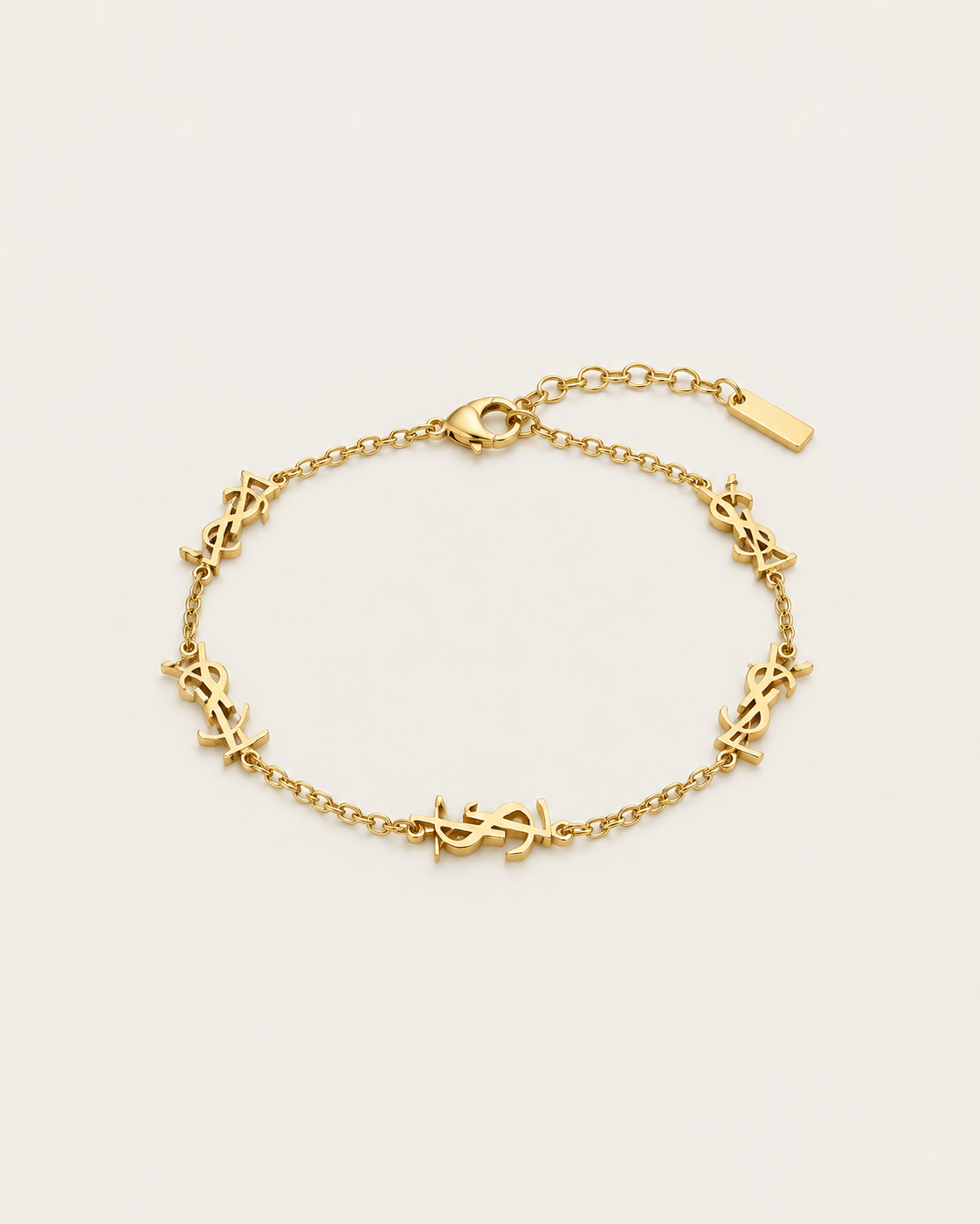 Gold-tone chain bracelet with repeated monogram-style stations, laid out.