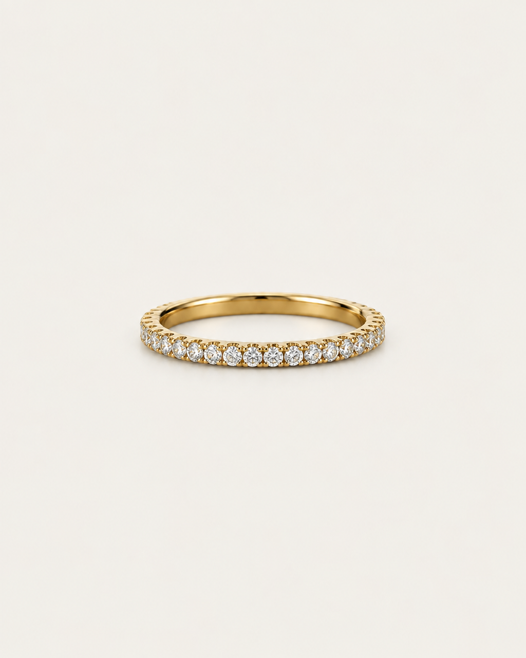 Gold-tone straight band ring with a row of pavé-style stone accents, front view.