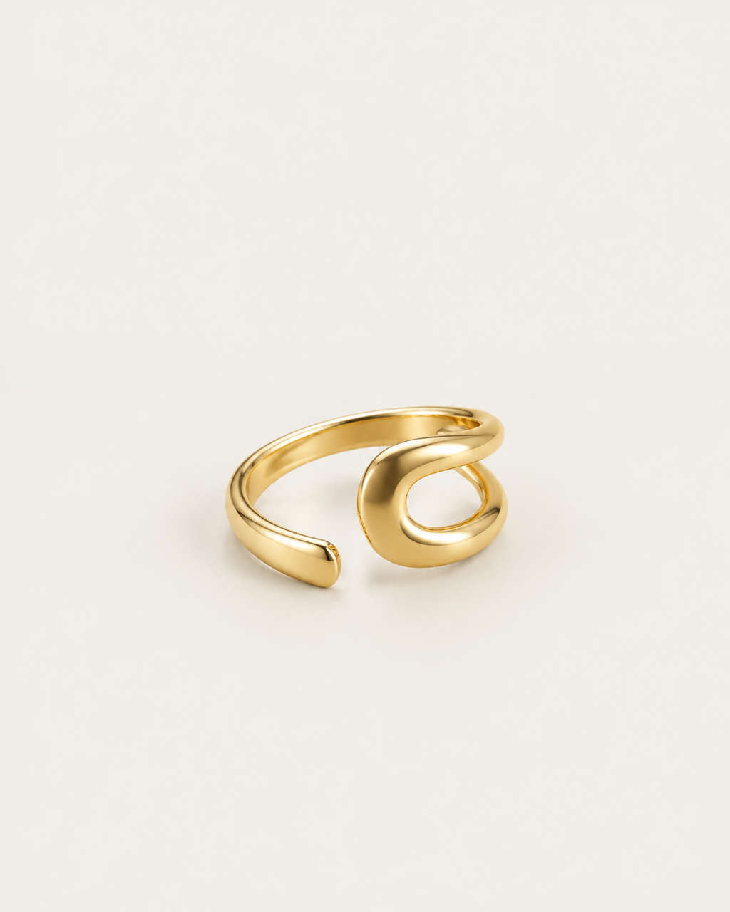 Gold-tone bypass ring with an open loop and tapered end, angled view of the loop and band.