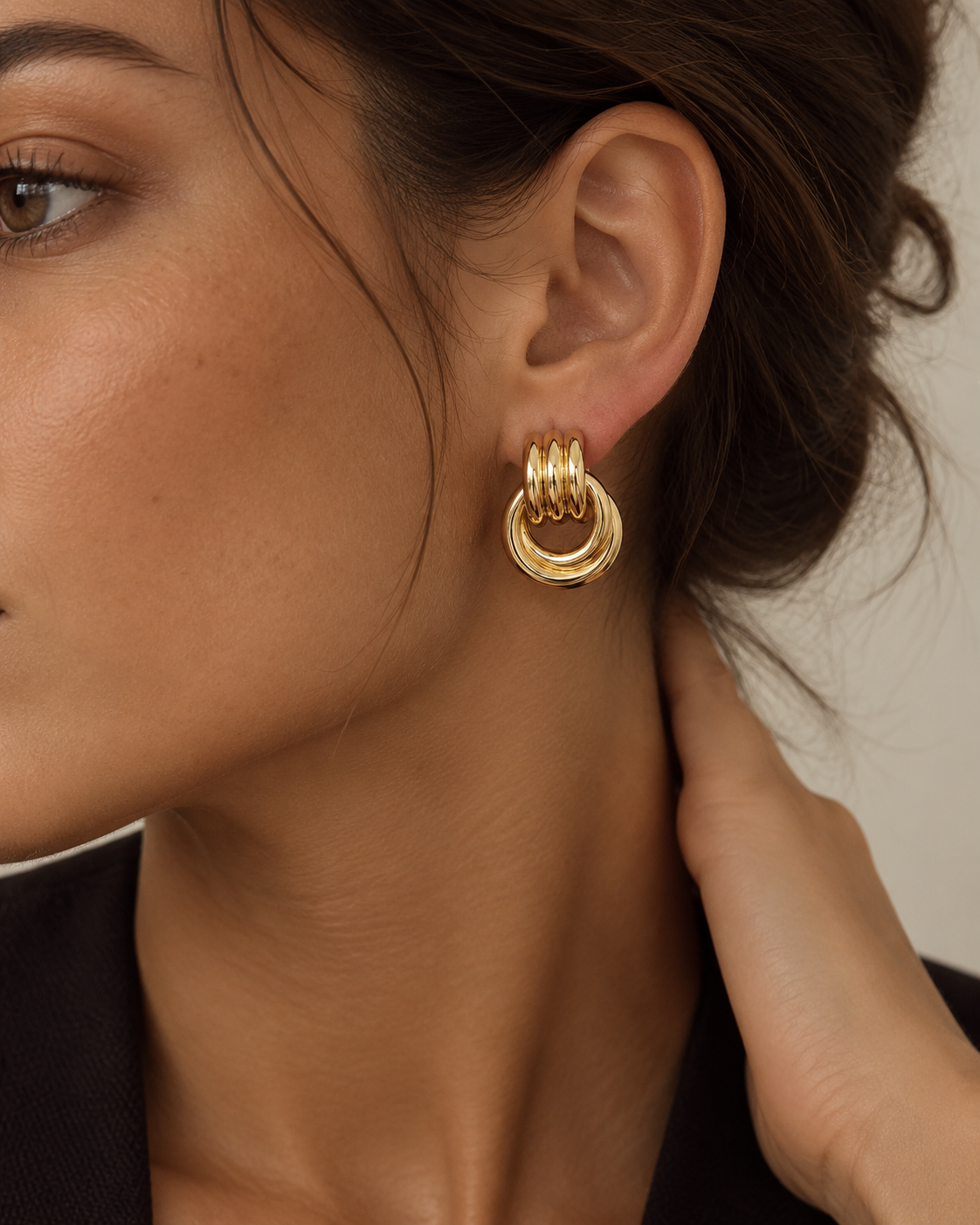 Close-up of a gold-tone circle drop earring on the ear.
