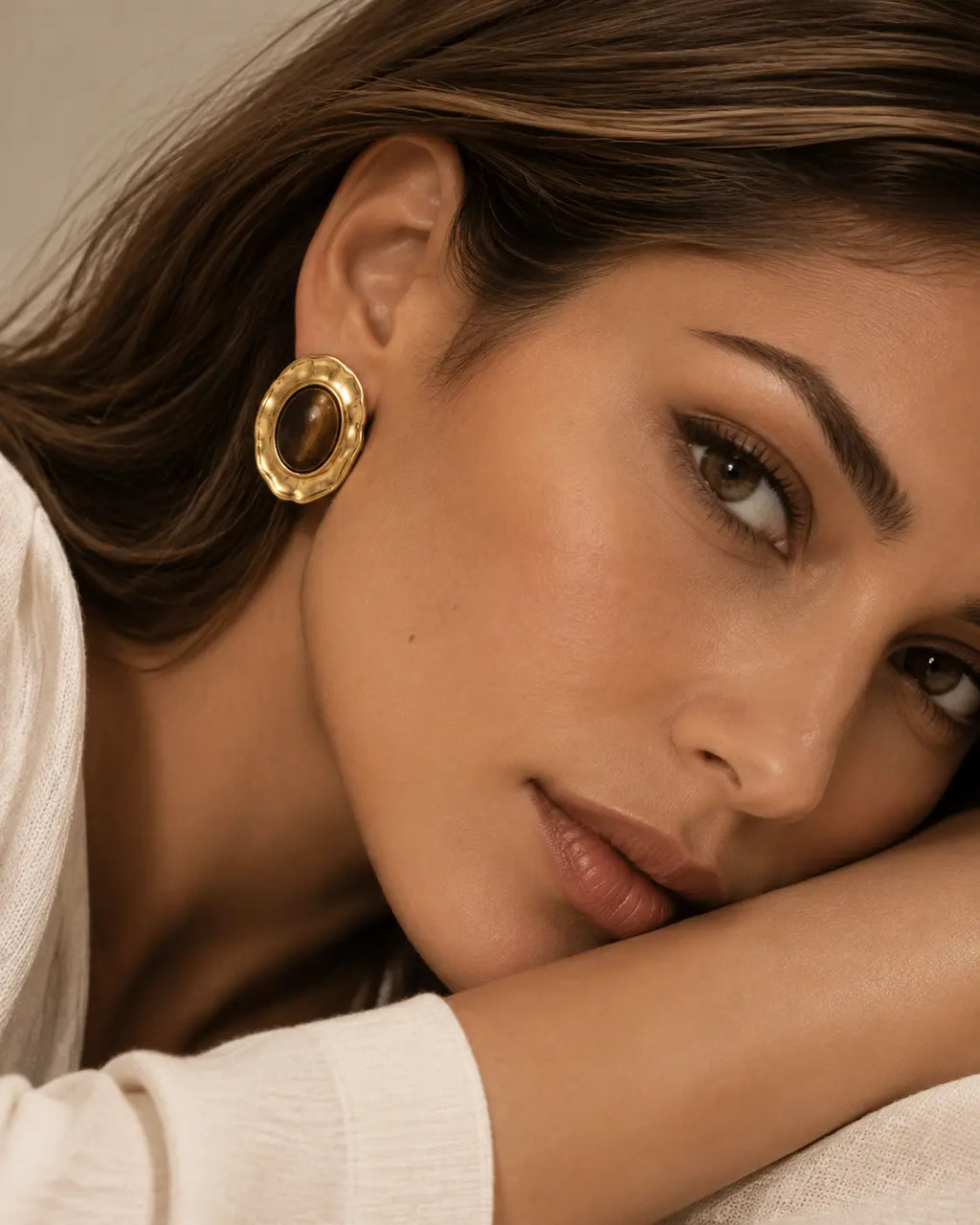 Brown oval stud earring visible with the head resting on a forearm.