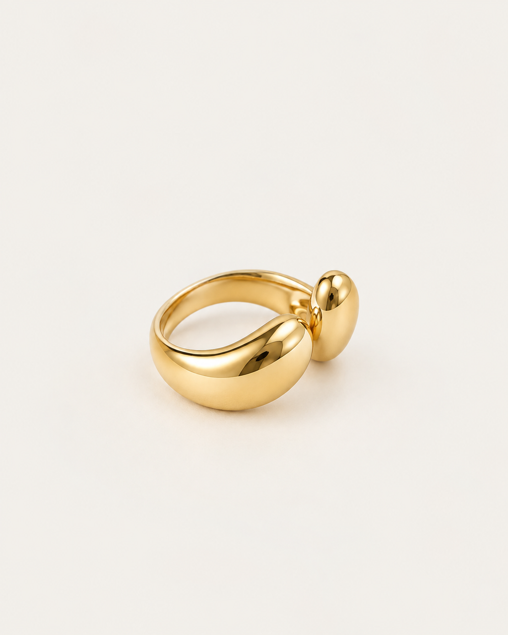 Gold-tone bypass ring with two rounded drop-shaped ends, angled view showing the band.
