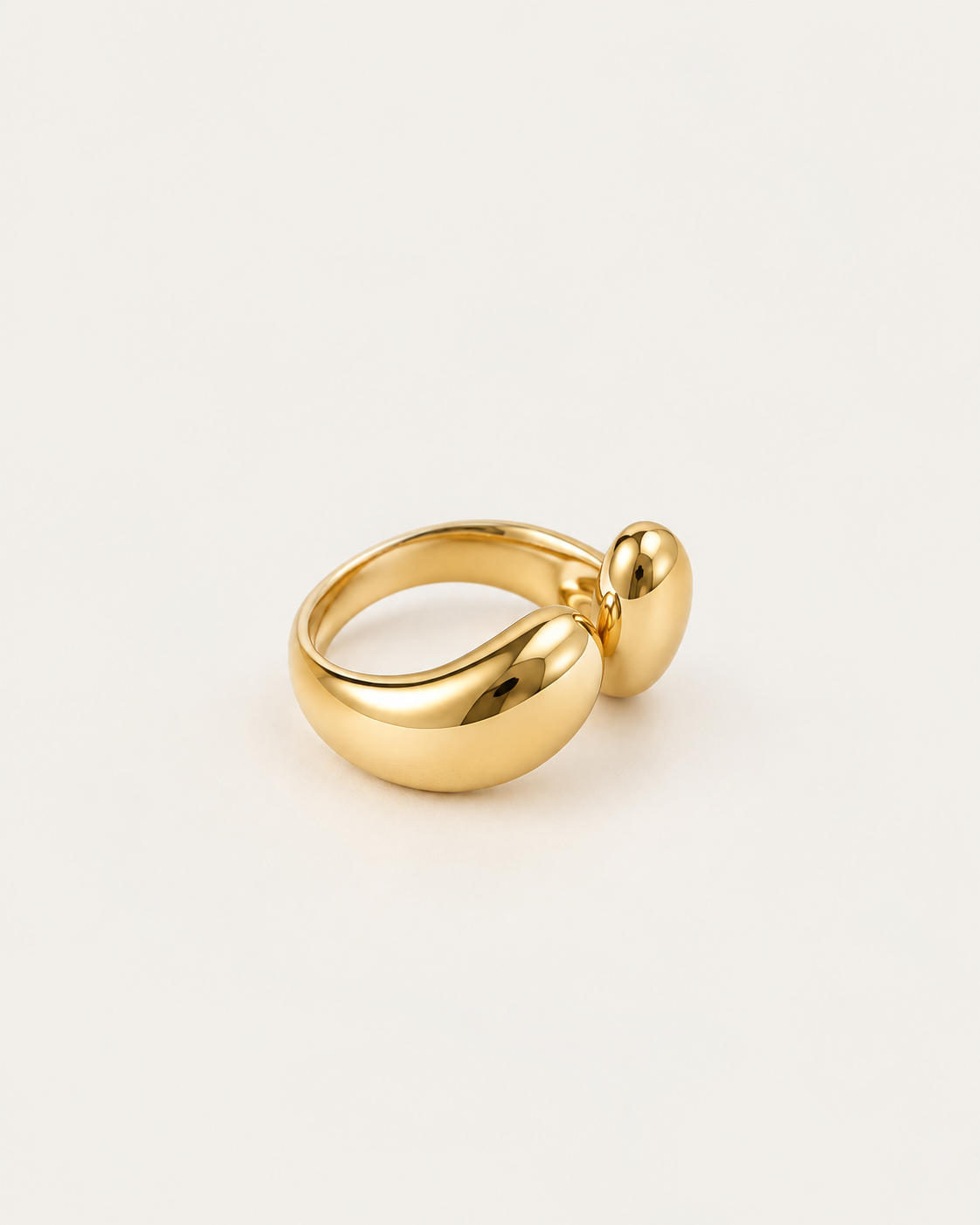 Gold-tone bypass ring with two rounded drop-shaped ends, angled view showing the band.
