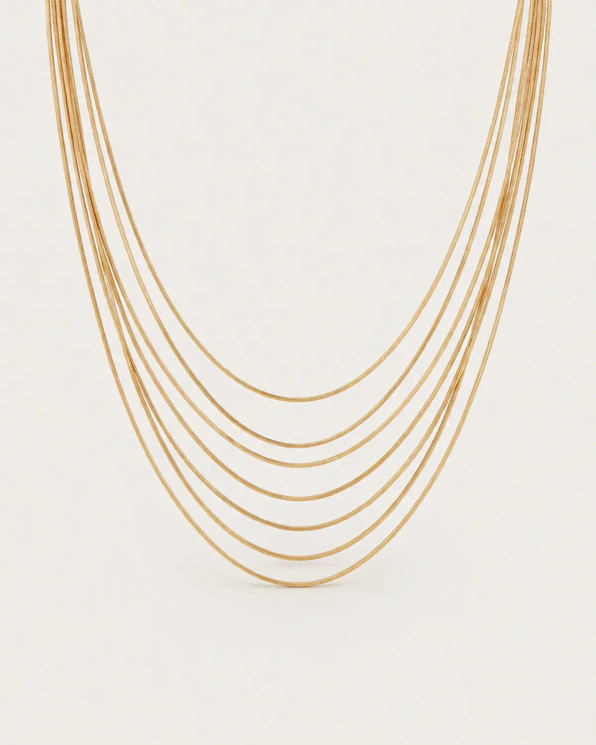 Gold-tone necklace with multiple fine chain strands in graduated lengths, displayed with its joined fastening.