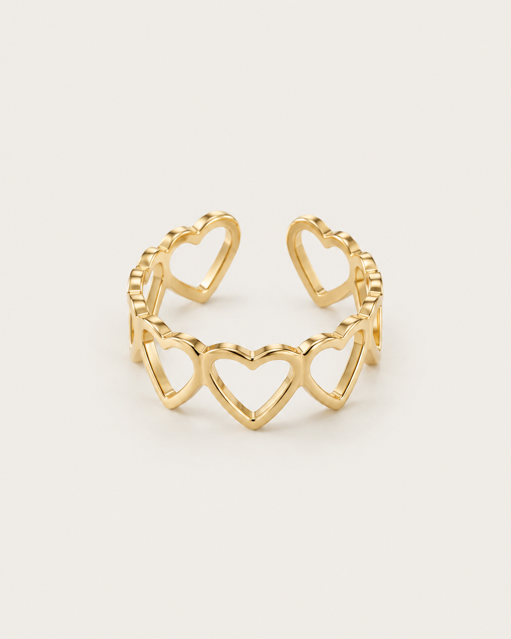 Gold-tone open band ring with linked heart outlines, front view.