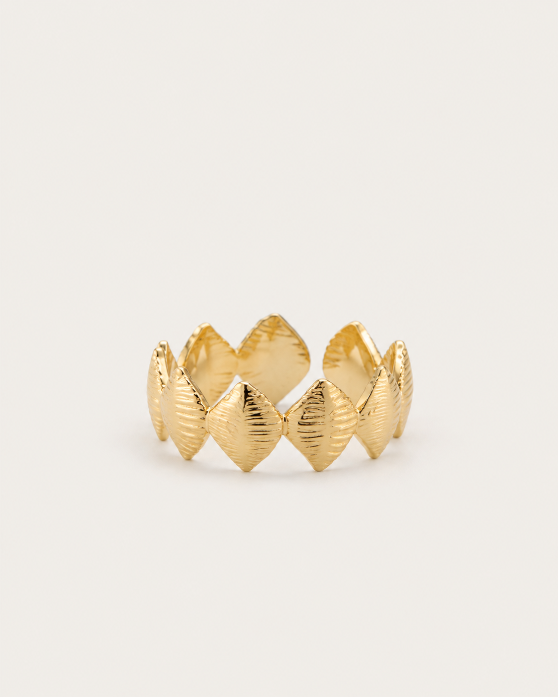 Gold-tone band ring with textured rhombus-shaped motifs, front view.