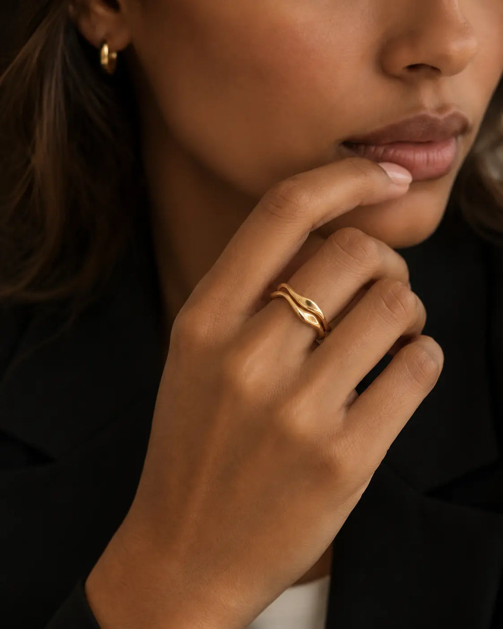 Set of two gold-tone wave stacking rings, close-up of the two rings worn together.