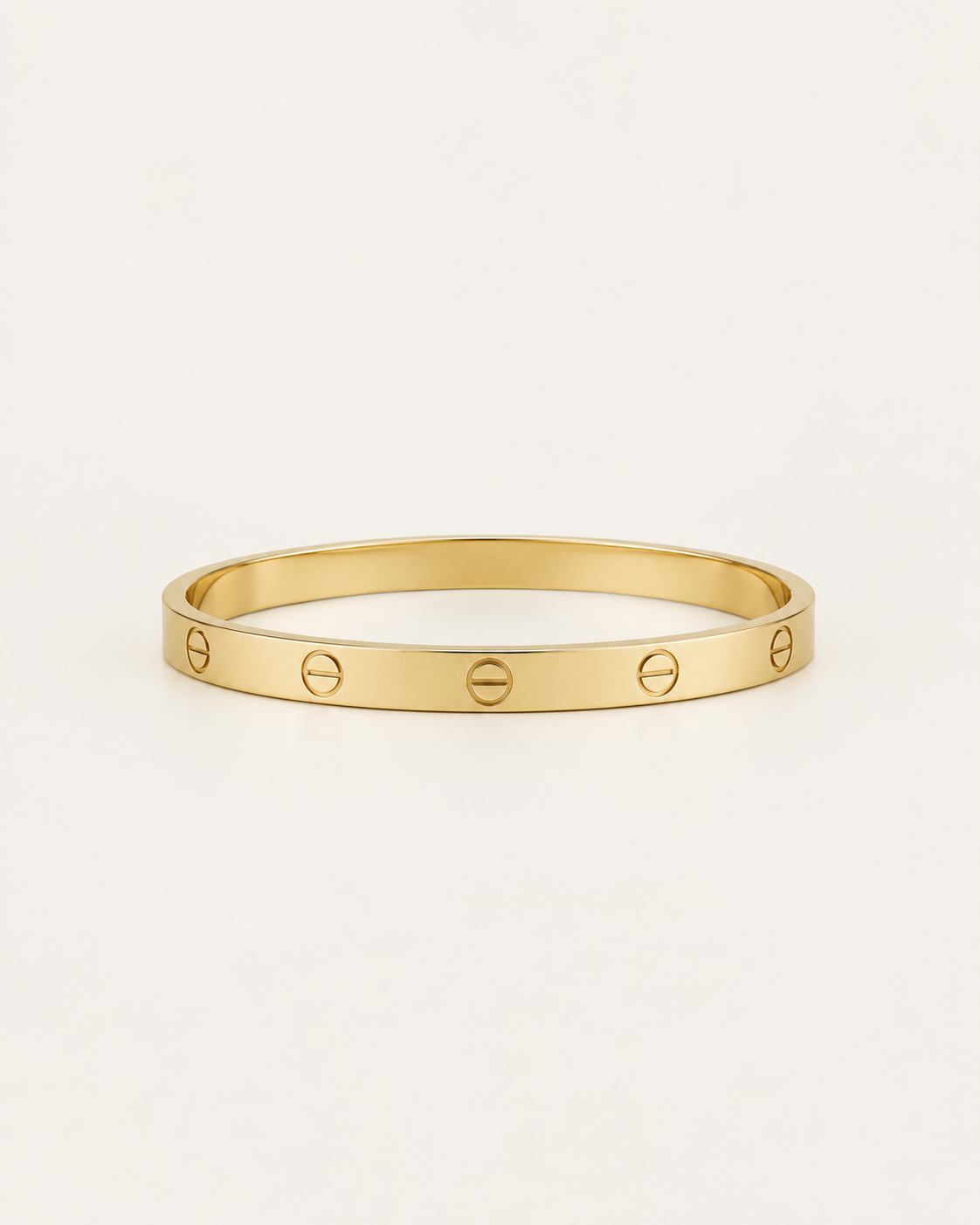 Plain gold-tone bangle with engraved screw motifs, front view.