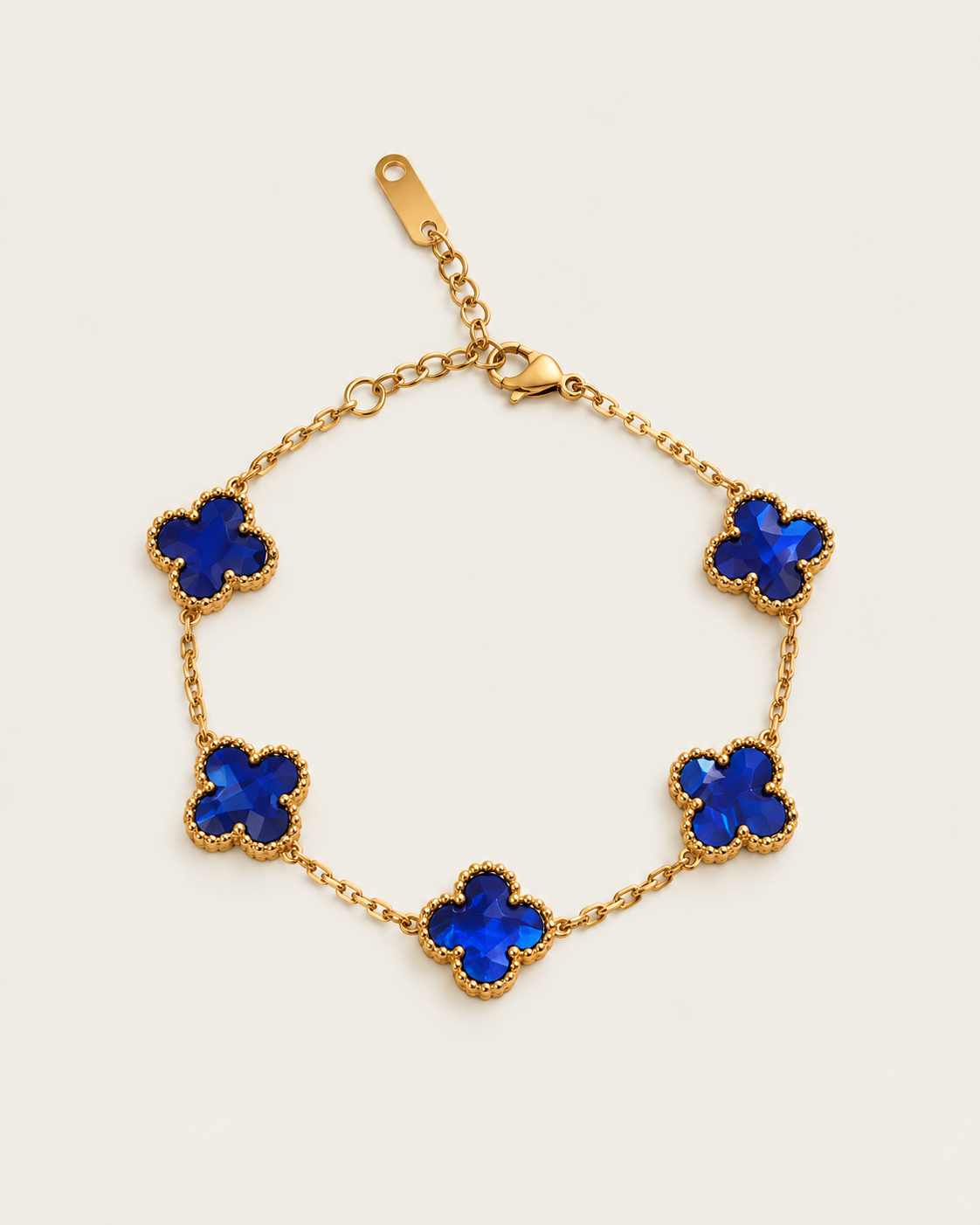 Chain bracelet with five blue-inlay clover stations, laid out on its own.