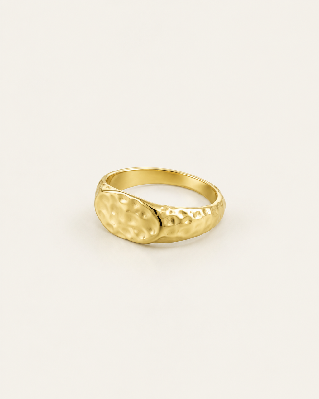Gold-tone ring with a hammered oval dome, angled view showing the band.
